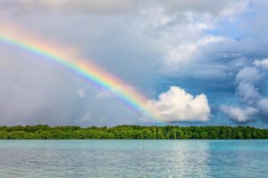 Rainbow through sky over water